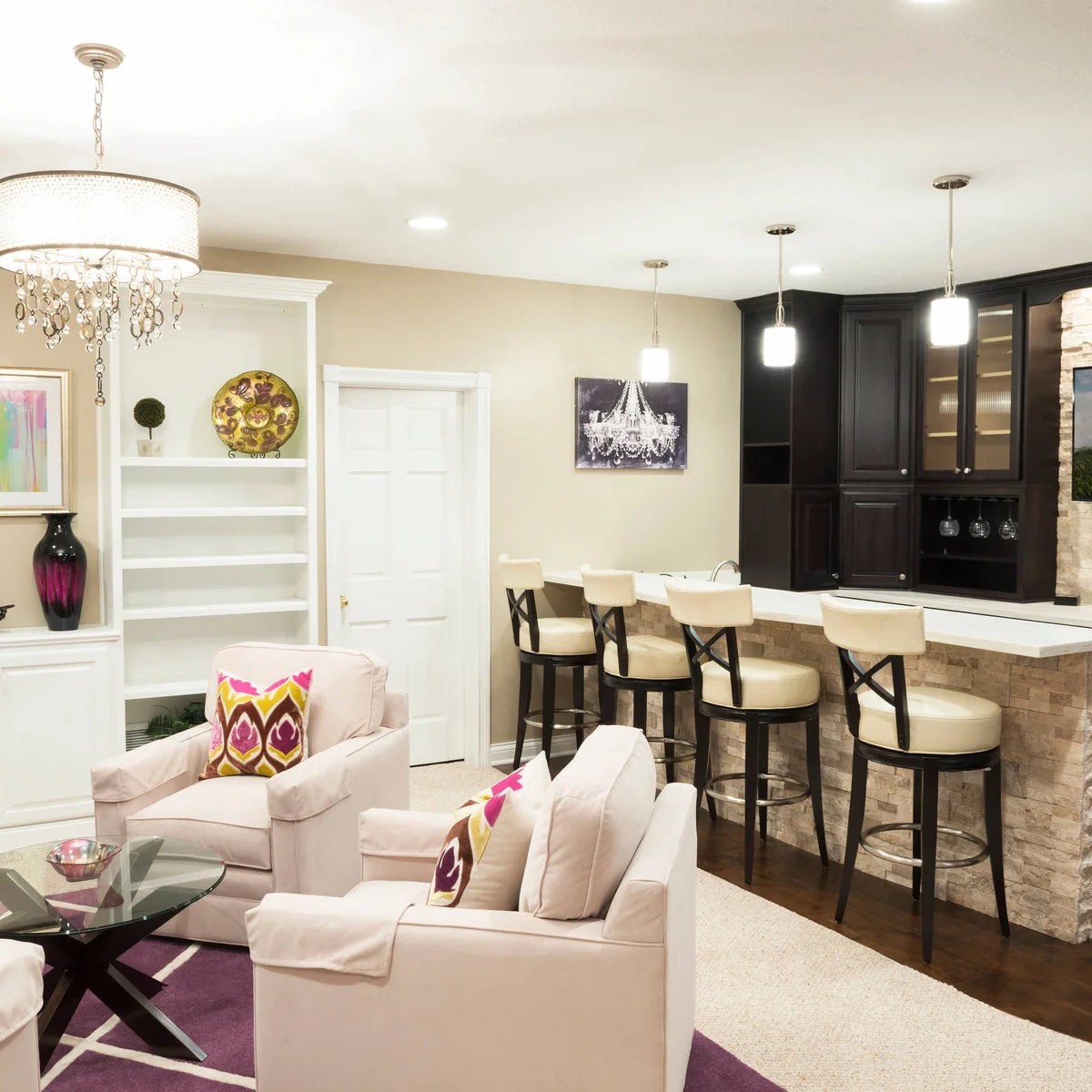 Basement bar with pale stools, dark upper cabinets and soft chairs in the adjoining sitting area