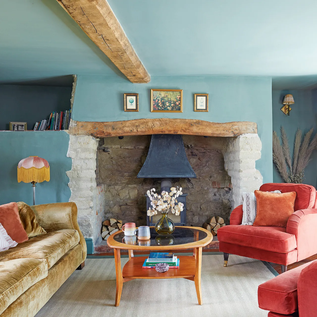 A turquoise room contains warm-colored chairs beside a stone fireplace