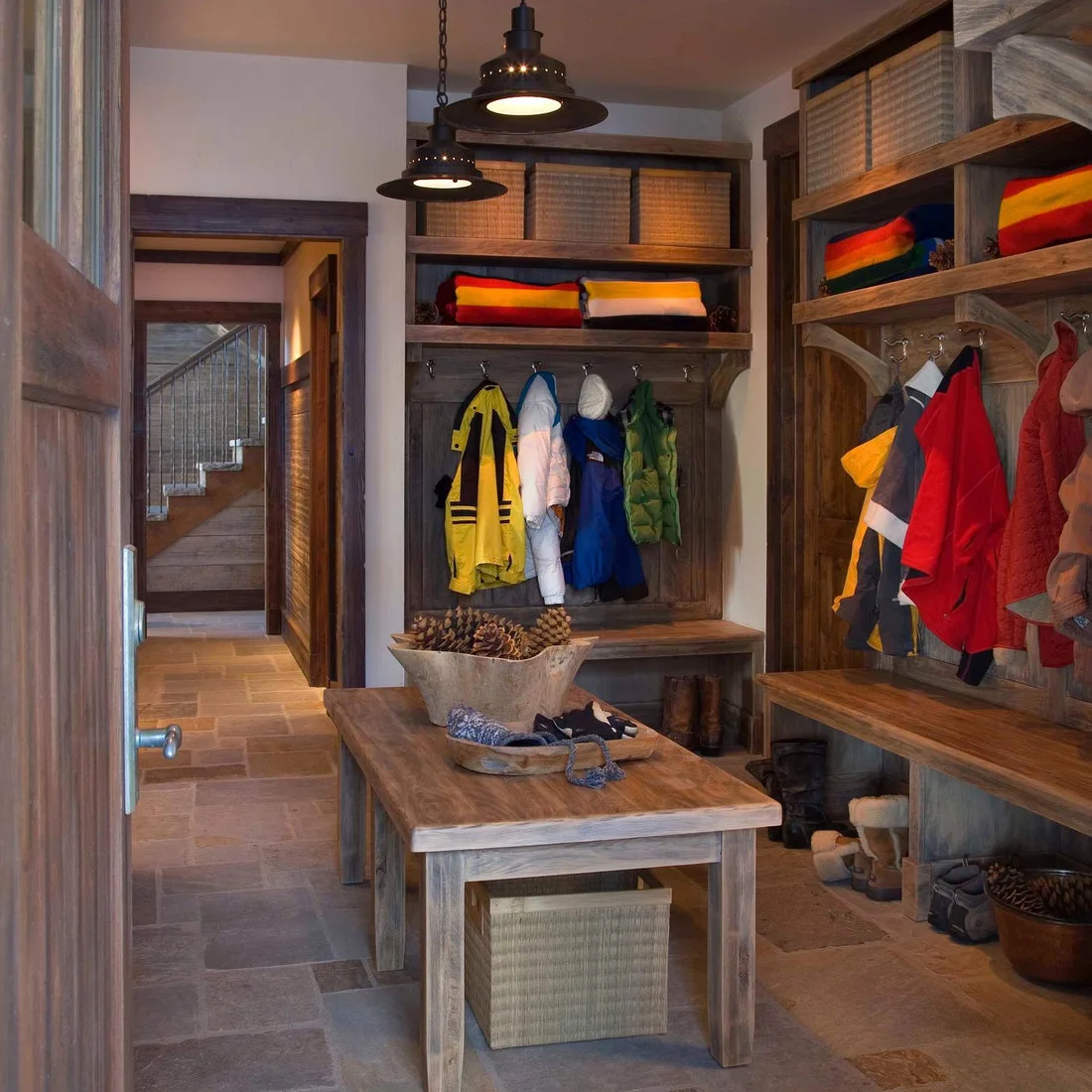Timber coat storage, benches and baskets around a freestanding table in a mudroom