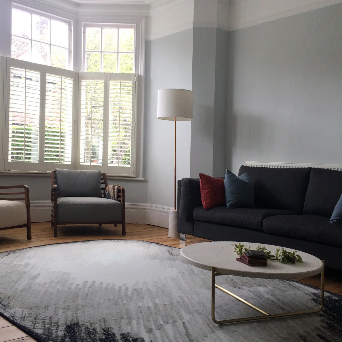 Dark sofa and wood-framed chairs around a large rounded pale rug and oval coffee table