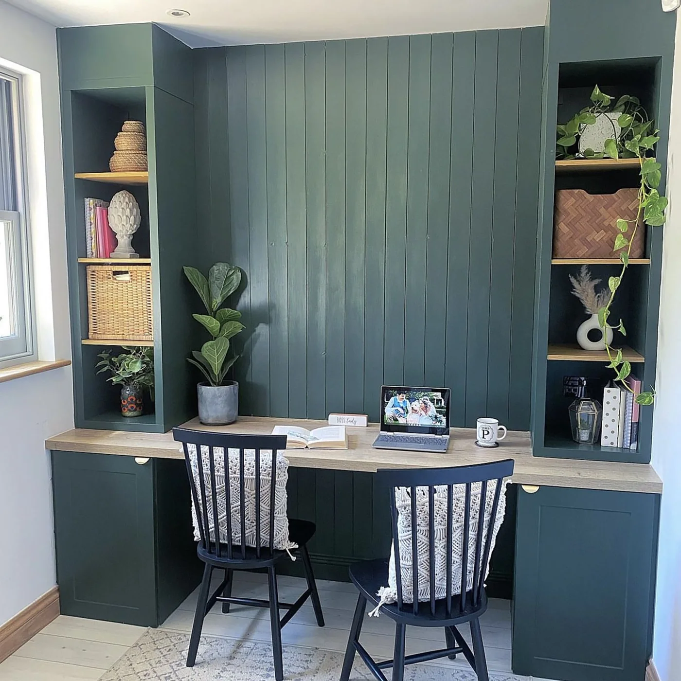 Green built-in desk with two chairs, tall side shelves and lower cupboards