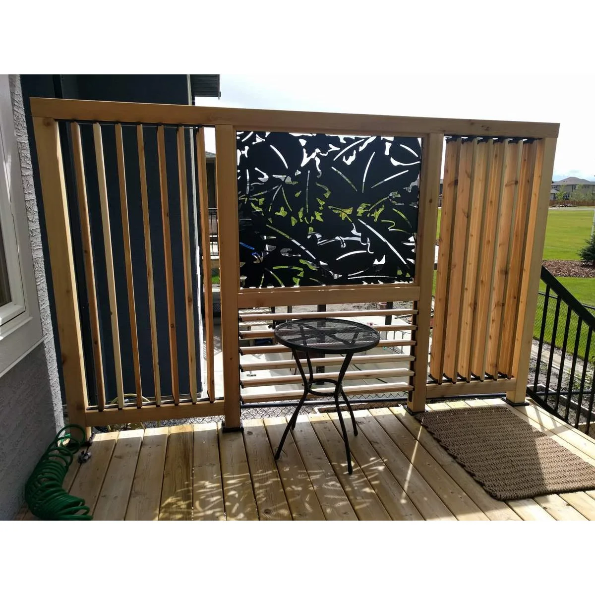 Vertical adjustable slats and a patterned central panel form a privacy screen beside a small elevated deck table