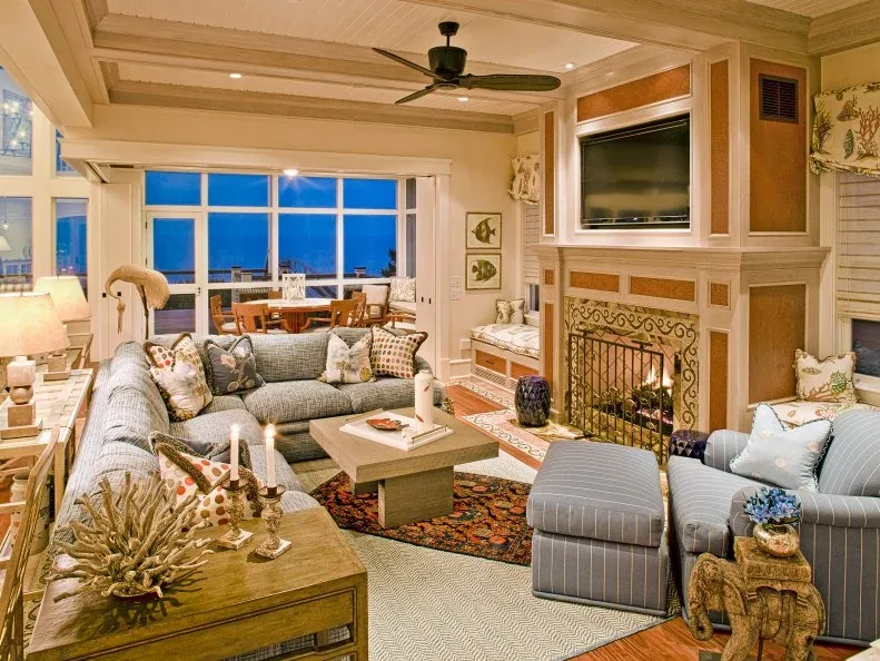 Pale blue seating around a small table beside a detailed fireplace and a wood-toned paneled ceiling.