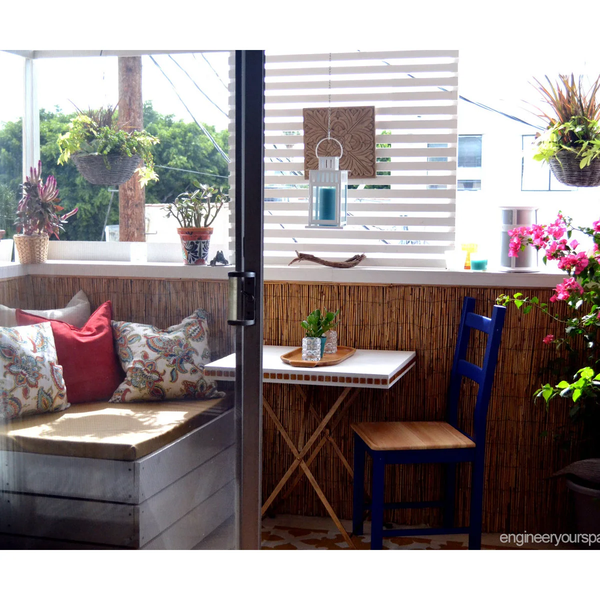 Small balcony with cushioned corner bench, blue chair, folding table and plants
