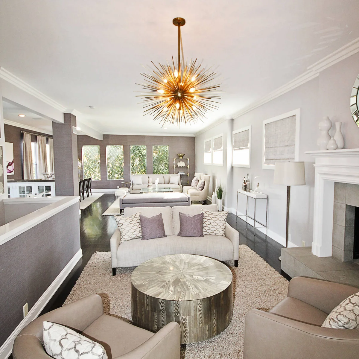 Elongated gray-and-white room with a small sofa and round table in front and a second seating group beyond