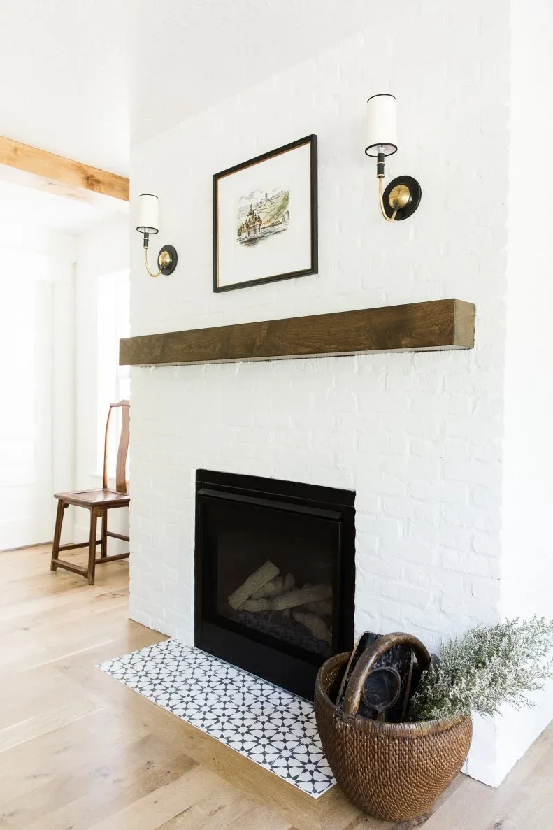 White brick fireplace with black and white patterned hearth, wood mantel and woven basket