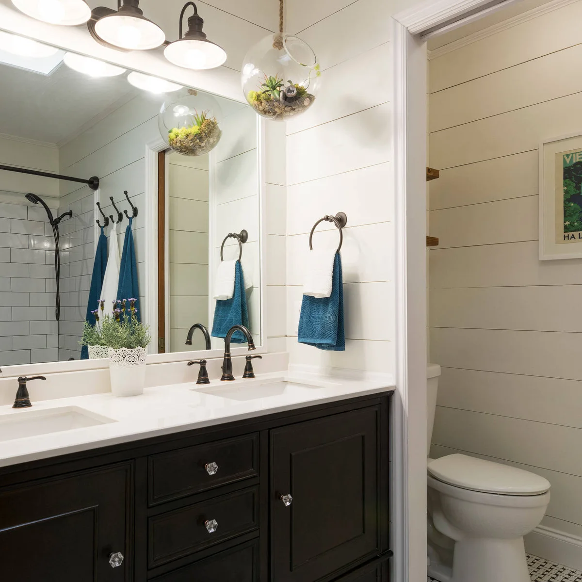 Dark vanity with clear faceted knobs, matching dark faucets and towel rings against white horizontal wall boards.