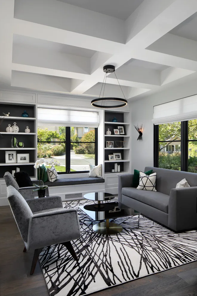 Dark gray seating rests beneath a white coffered ceiling in a room with black shelving