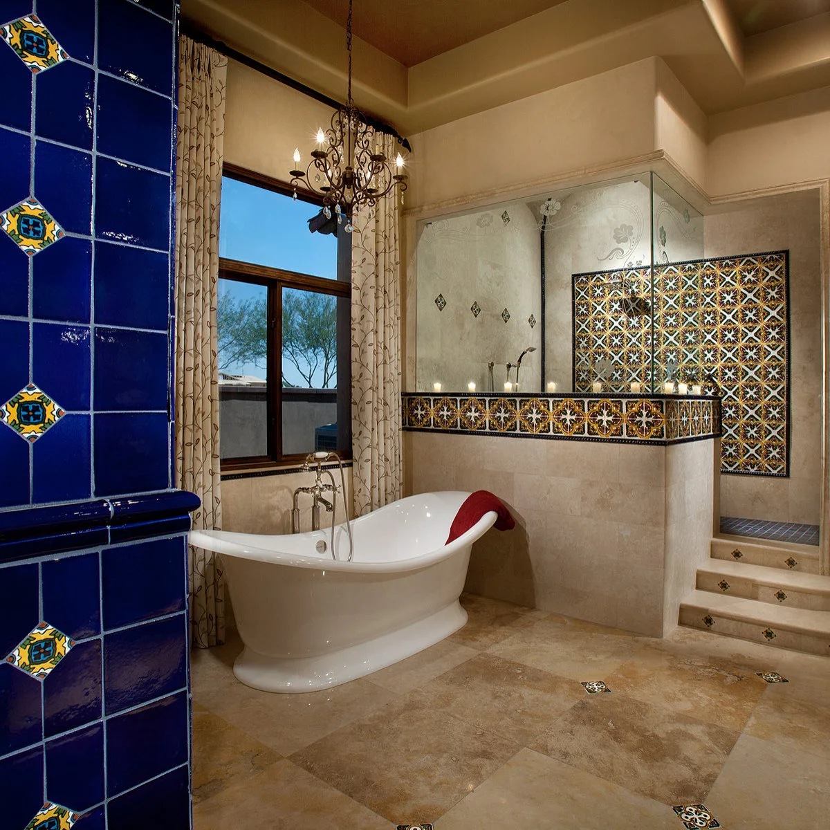 Bathroom with a deep blue tiled foreground wall, patterned shower panel and small colored floor inserts