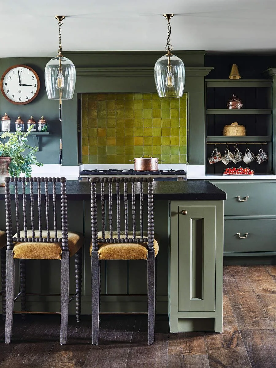 Yellow-green square tiles sit within a darker green range surround beside open shelves and a dark-topped island