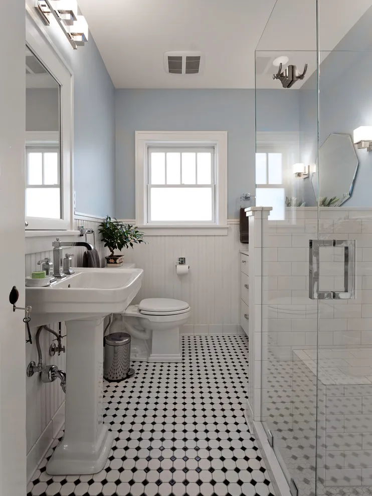 Small black-and-white tiles cover a narrow bathroom floor beneath a wall-mounted sink