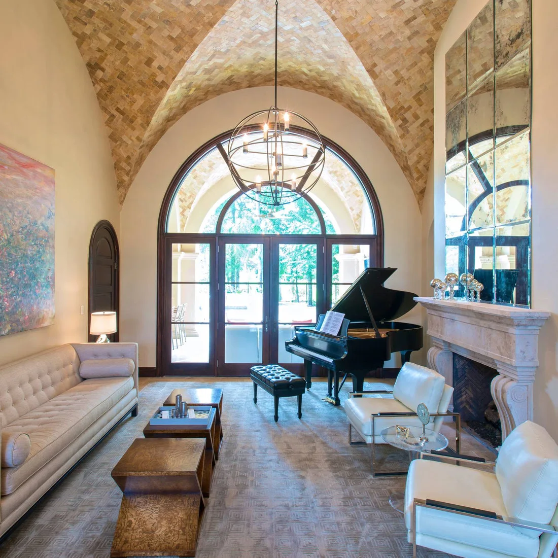 A warm brick-patterned vaulted ceiling rises above an arched glazed door beside a black piano, pale tufted sofa and two pale chairs