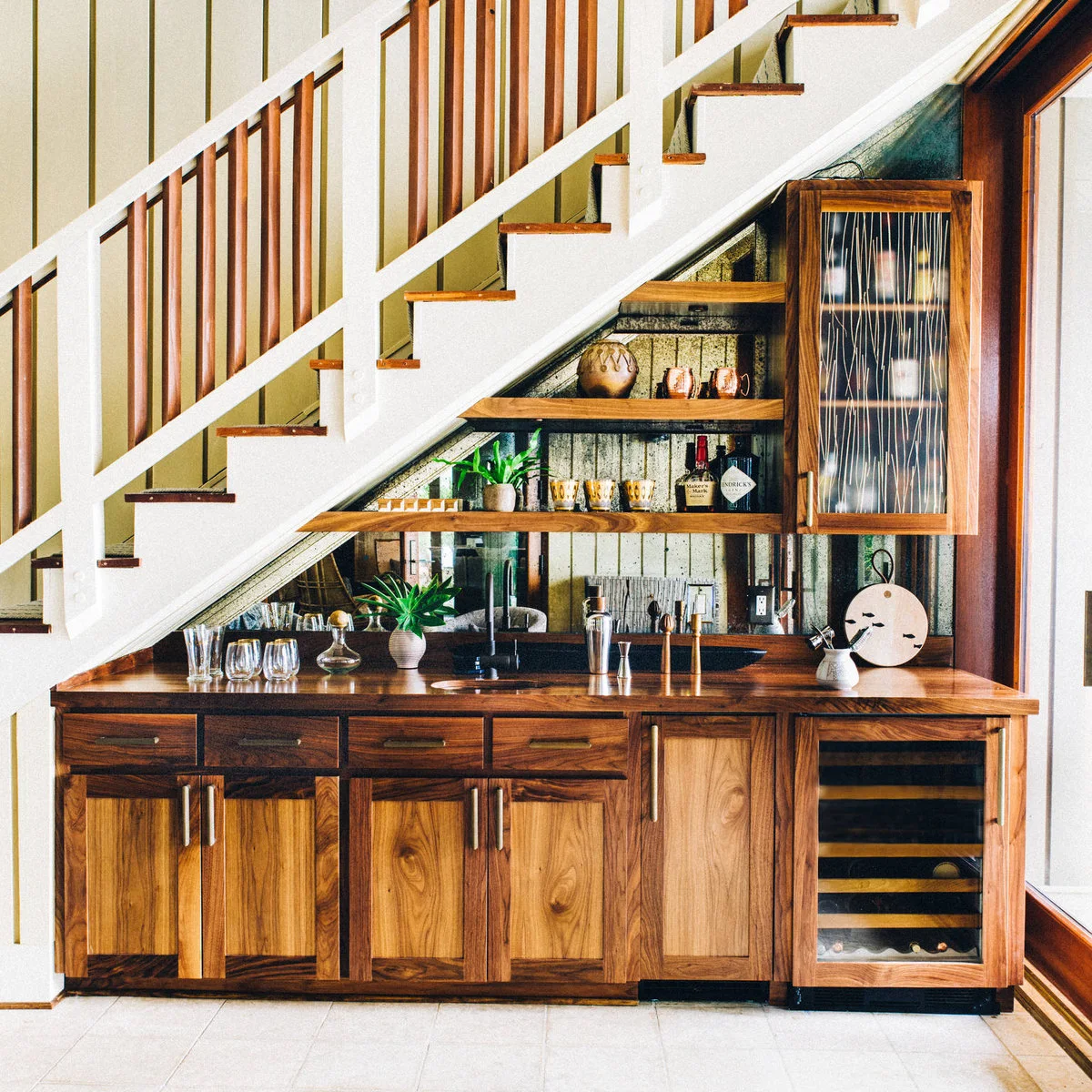 Under-stair mini bar with wood cabinetry, staggered shelves, a small sink and wine refrigerator