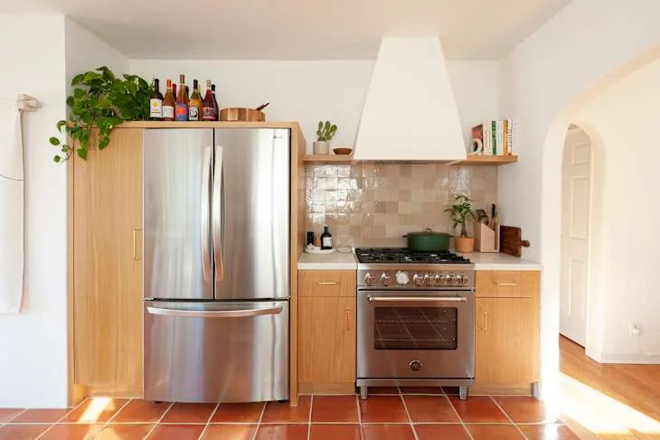 Wood-front cabinets, stainless steel range, cream handmade-look tile and sculptural plaster hood