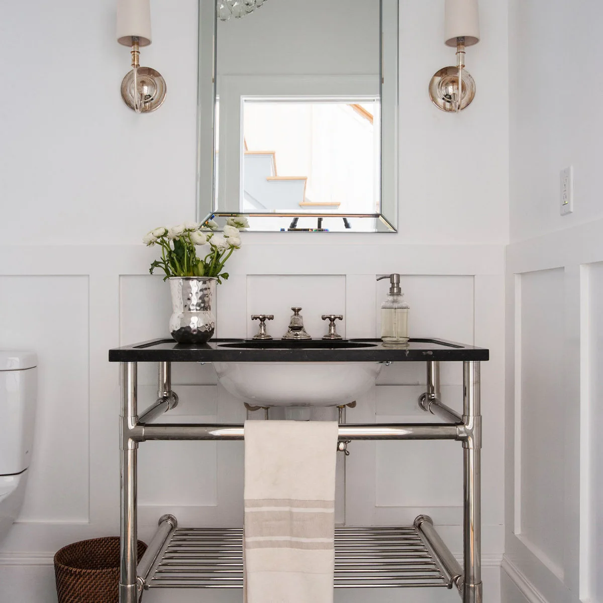 White lower rectangular paneling behind an open metal console basin and wall mirror