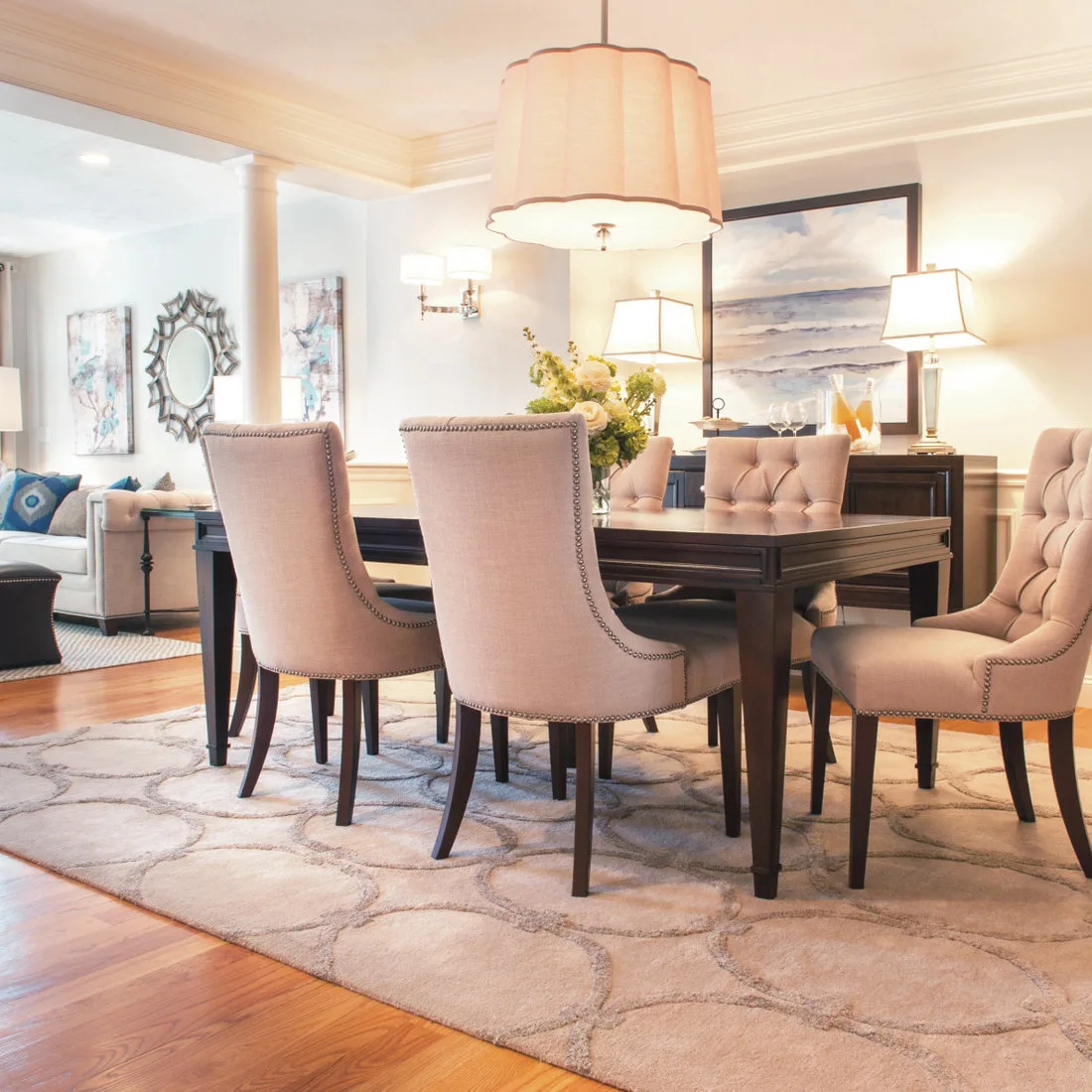 Pale rug with rounded gray outlines beneath blush-toned dining chairs and a dark rectangular table