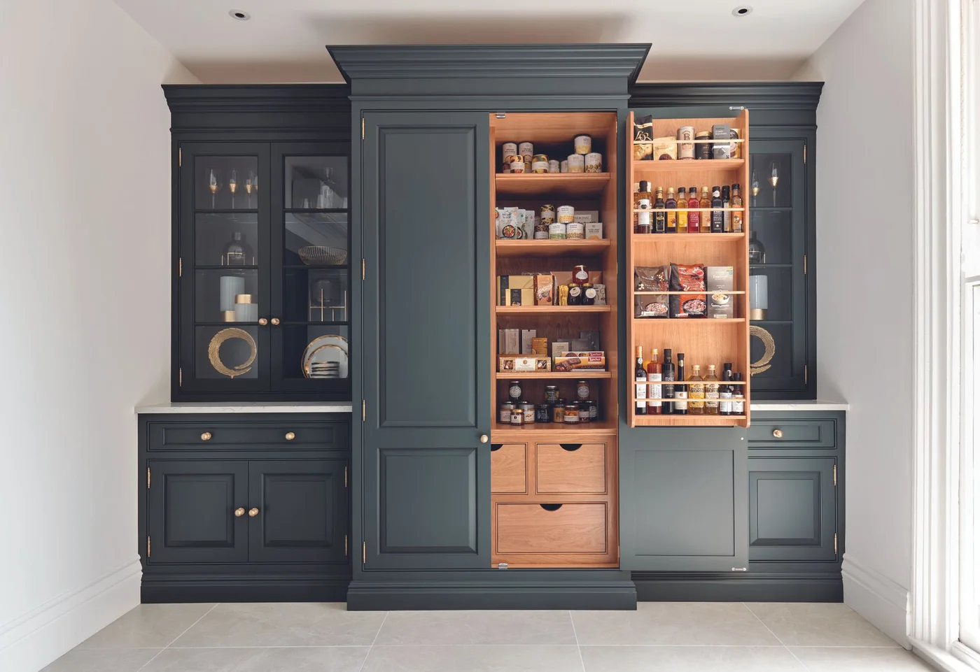 Dark blue cabinet wall with food larder in the middle and glazed dish cupboards at the sides