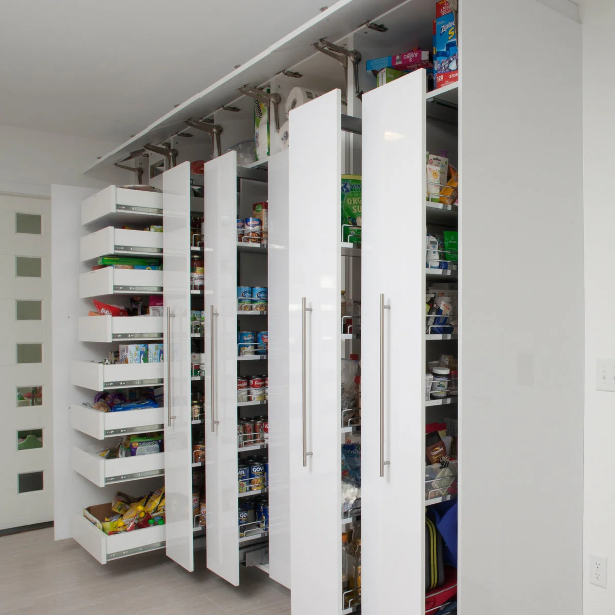 Wall of tall white pantry cabinets with narrow pull-outs and drawers extended