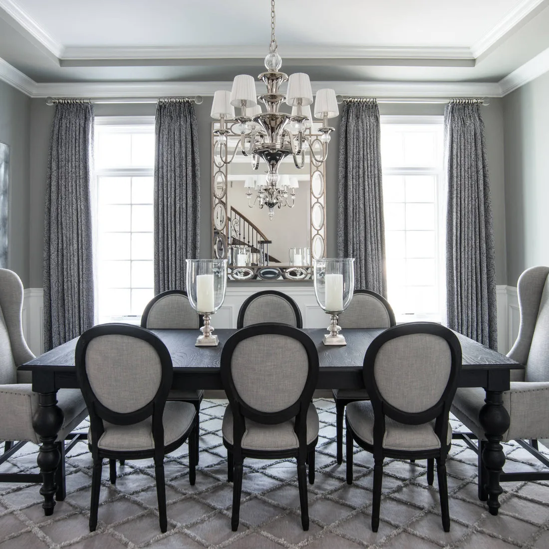 Pale gray diamond-patterned rug beneath a dark dining table and oval-backed gray chairs