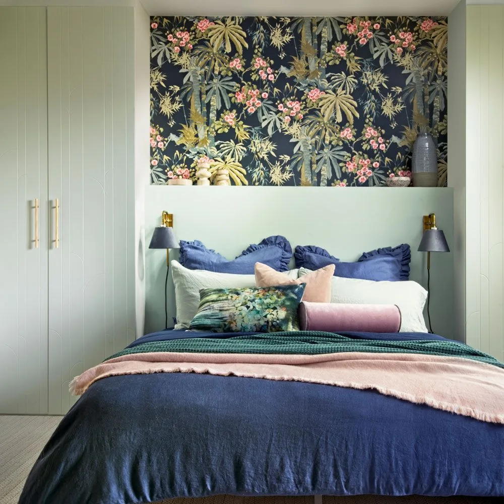 Pink flowers and pale foliage on dark wallpaper above mint paneling in a bedroom alcove.