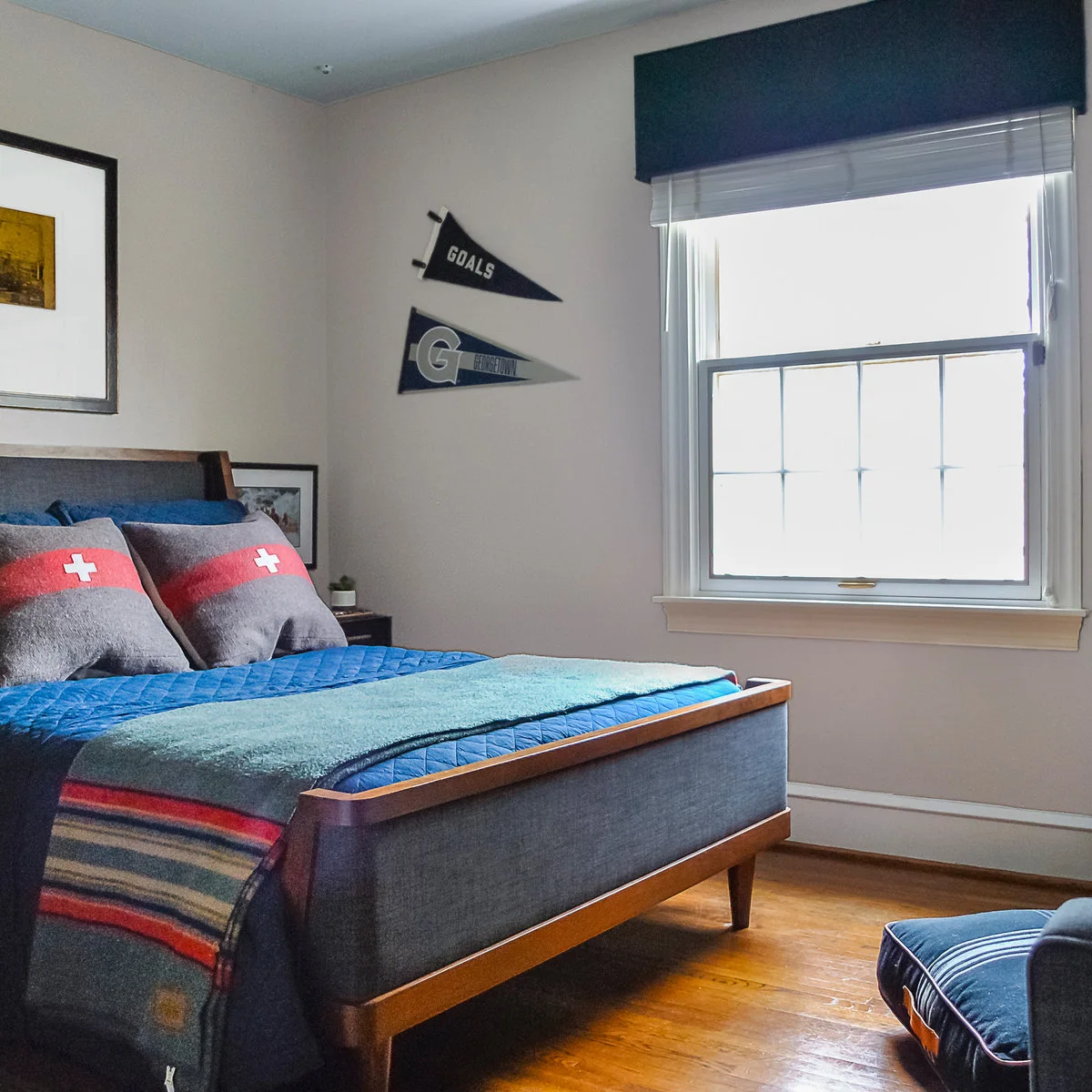 Teen bedroom with blue bedding, a striped blanket, pennants and the edge of a blue sofa