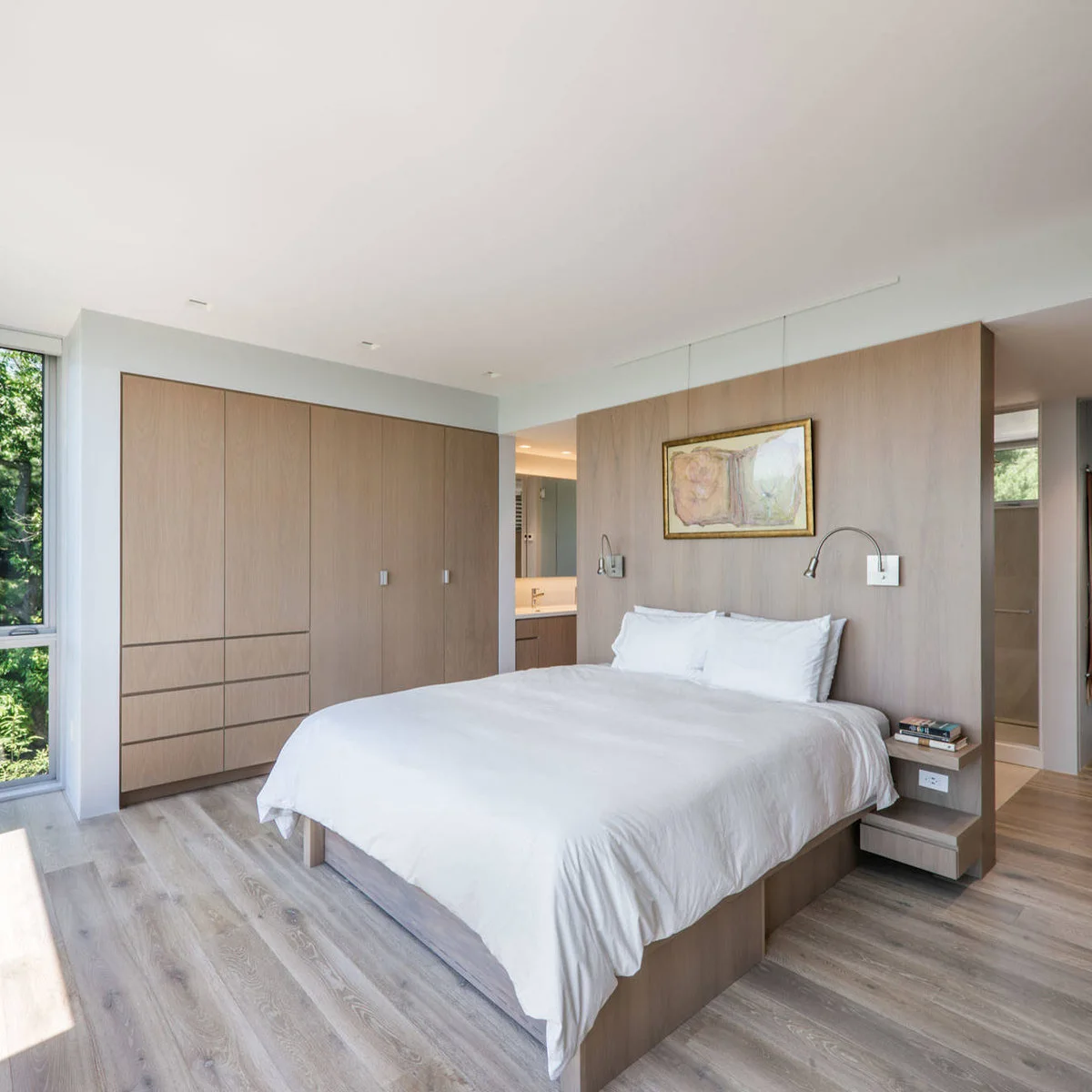 A pale wood bed wall with two adjustable lights and small shelves beside a broad fitted wardrobe.