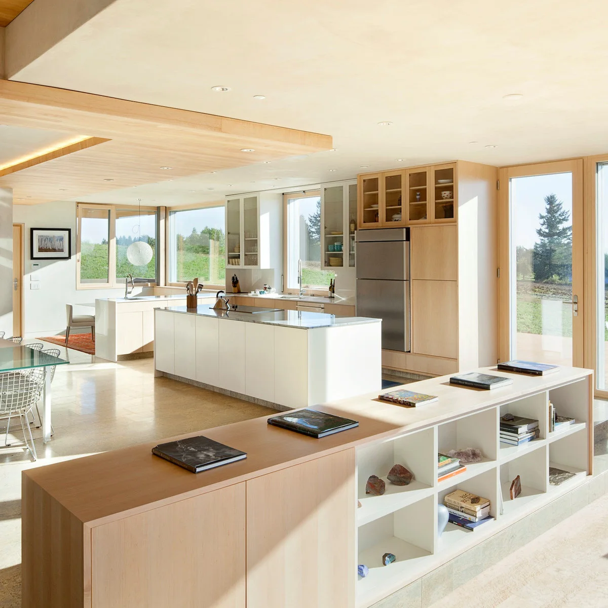 A long low cabinet with wood doors and white open cubbies stands in front of a bright kitchen.