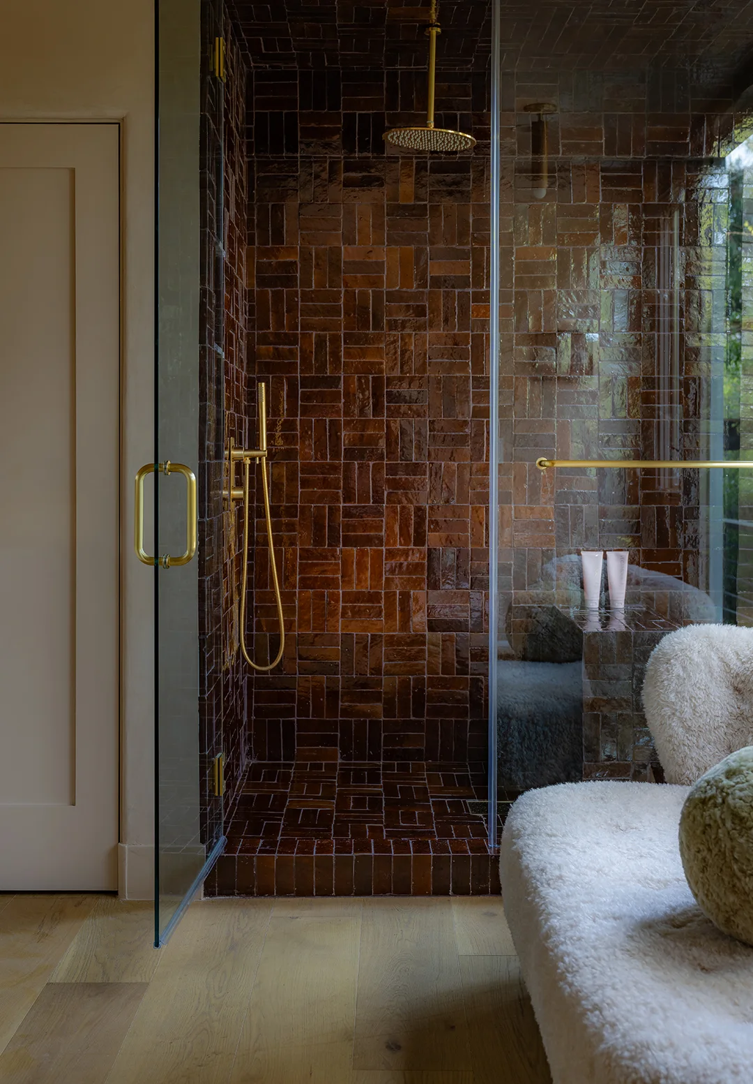 A glass shower enclosure contains dark brown rectangular tiles in an alternating basketweave arrangement