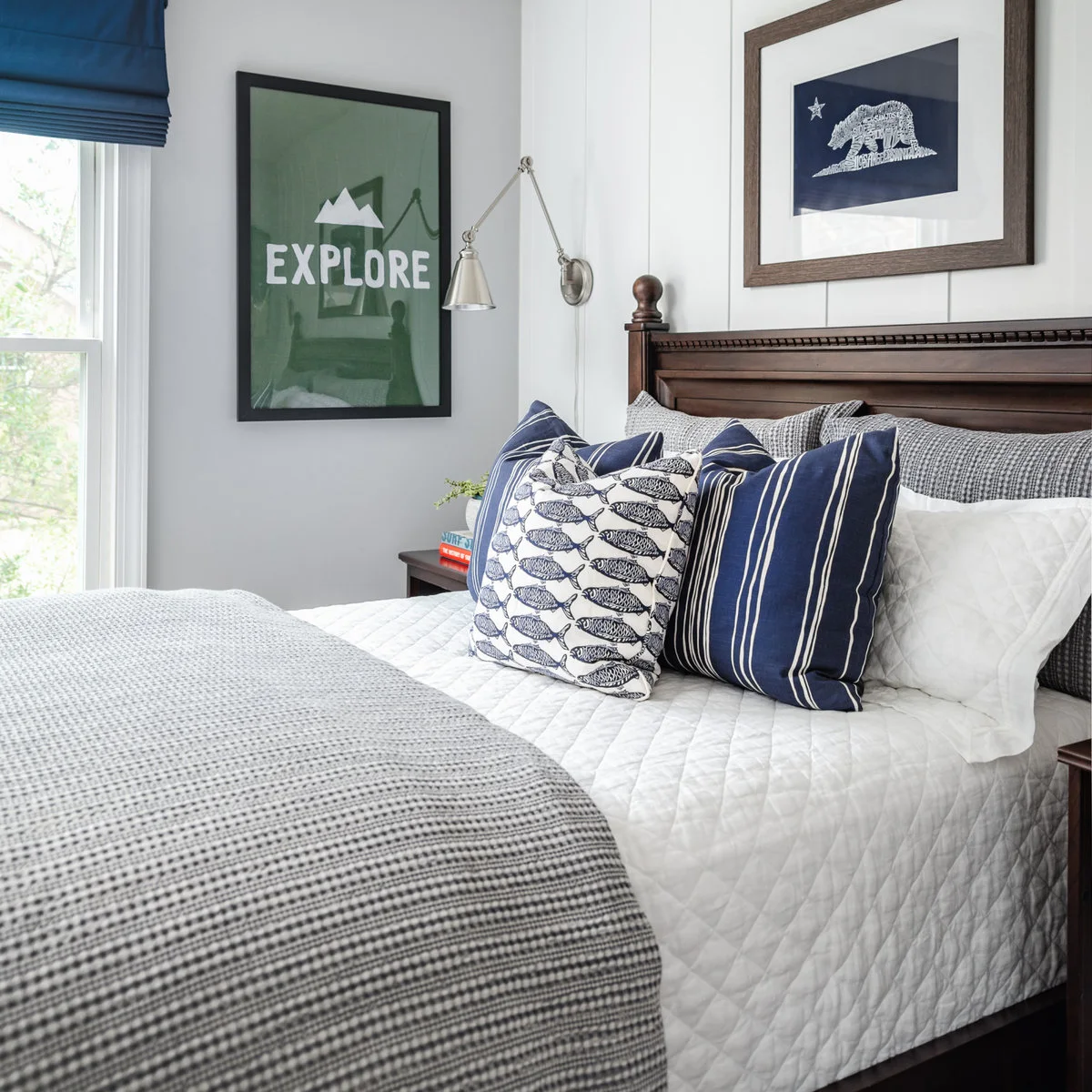 Teen bedroom with dark wood-colored headboard, blue striped pillows and outdoor-themed framed art