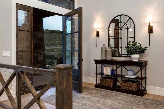 A narrow timber console sits beneath an arched mirror between two wall lights.