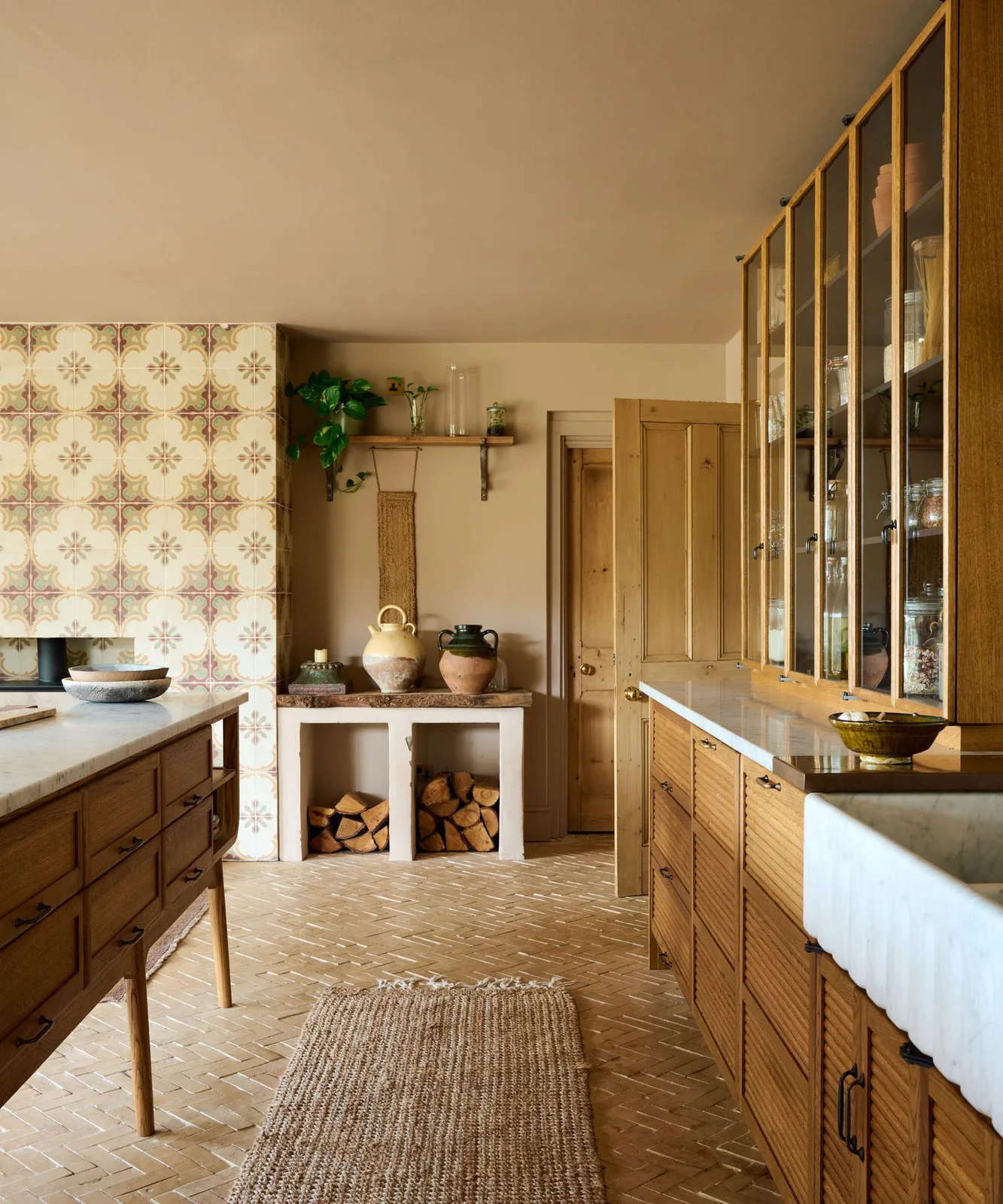 Warm galley-style kitchen with wooden drawer units, glazed cupboards and patterned tile at the end
