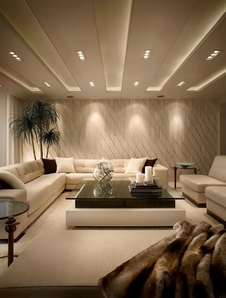 A beige sectional surrounds a low table beneath a long row of ceiling lights