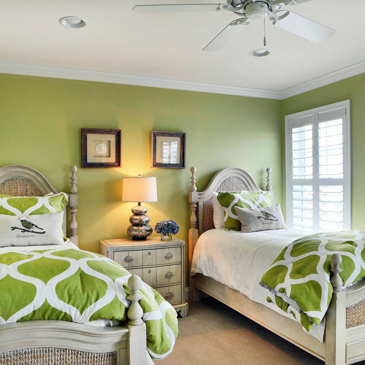 Two pale woven-detail beds with green and white bedding, bird cushions and a shared light chest