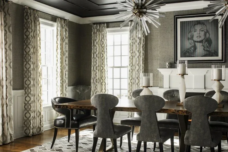 Gray dining room with a dark paneled ceiling, curved chairs, patterned curtains and a starburst chandelier.