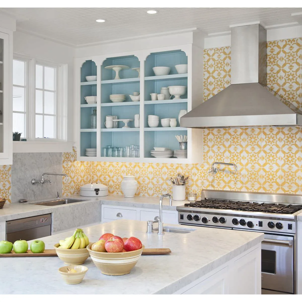 White kitchen with patterned yellow backsplash tiles and blue-backed open dish shelves