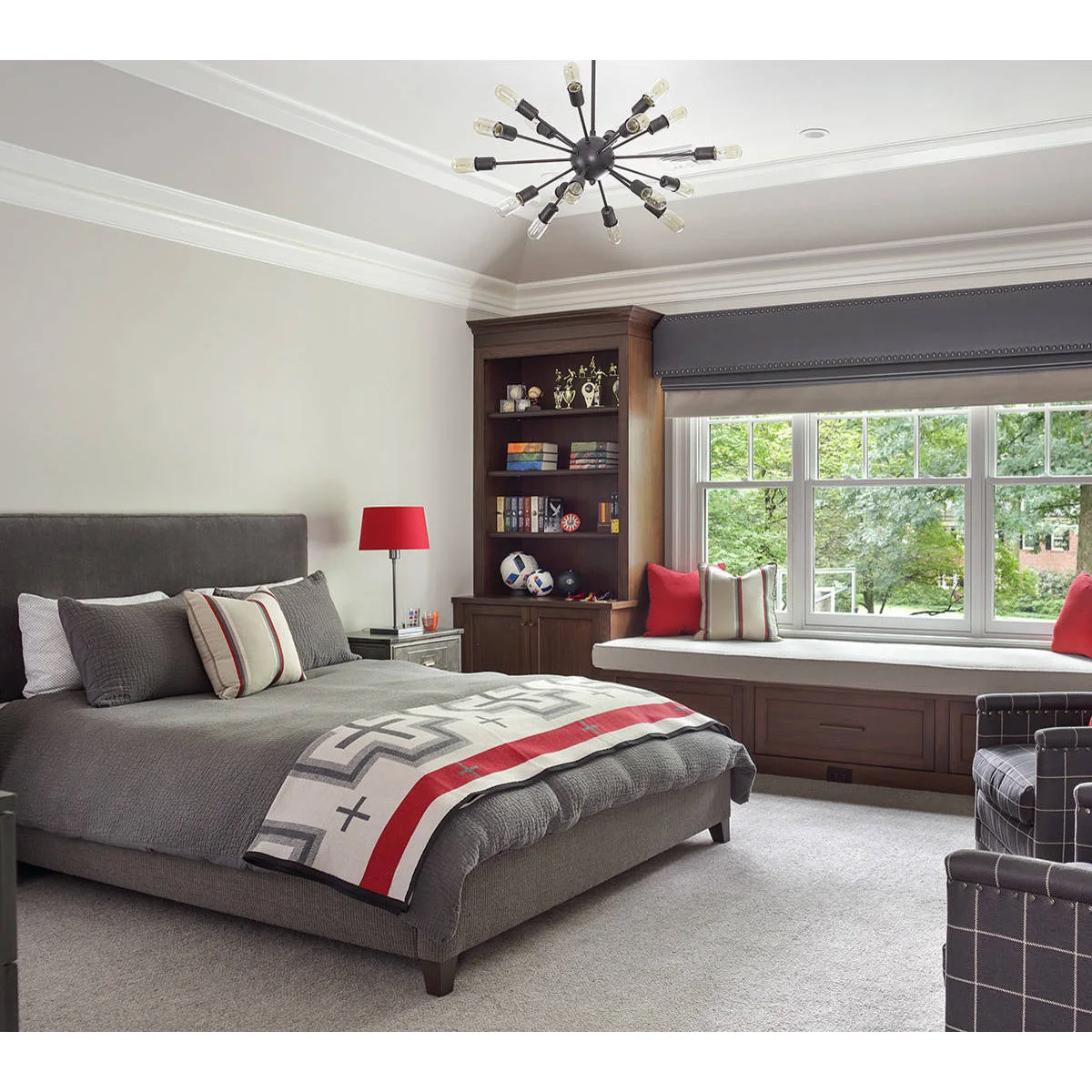 Gray teen bedroom with a window bench, red accent lamp and built-in book storage