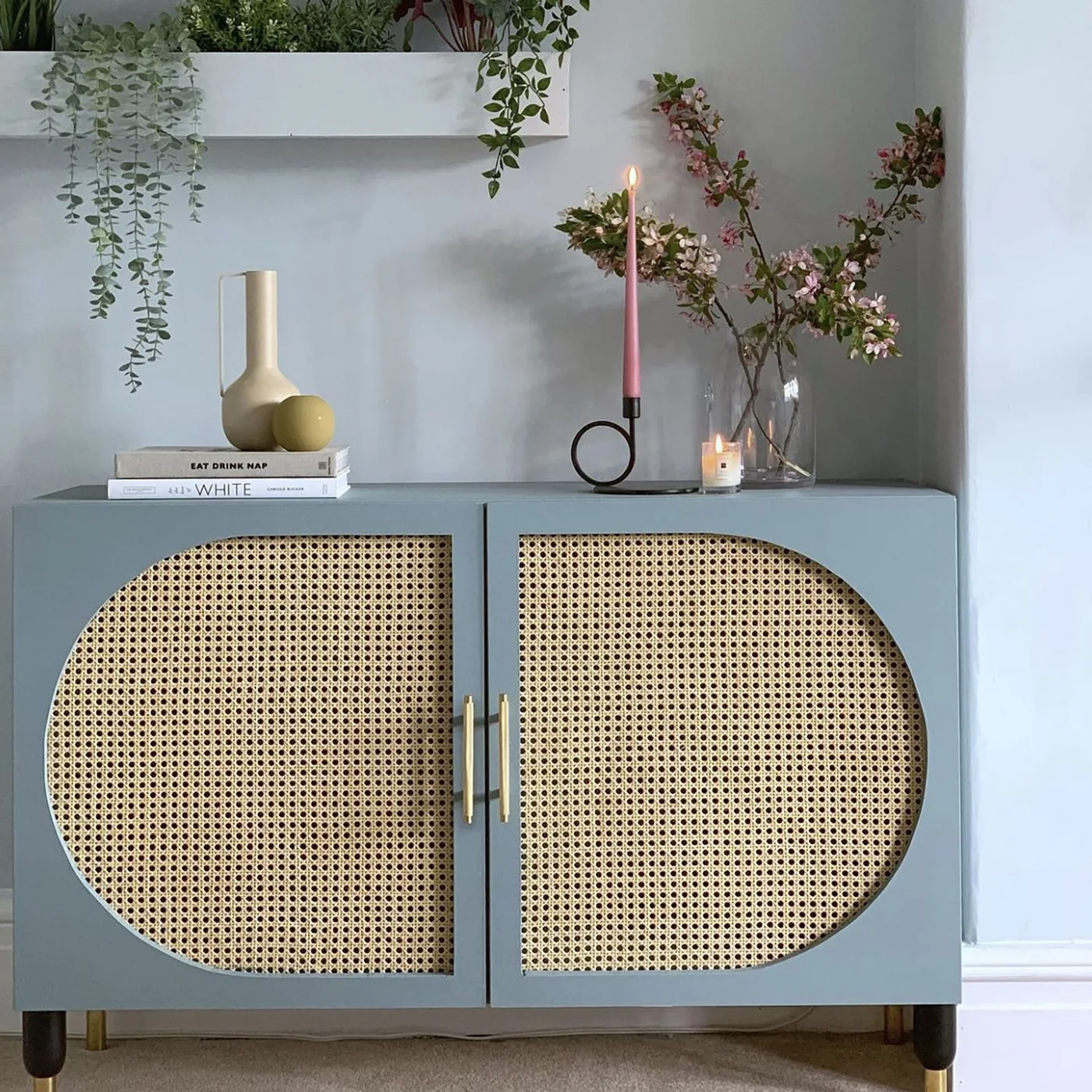 Blue-gray cabinet with curved cane door panels and long gold-colored handles