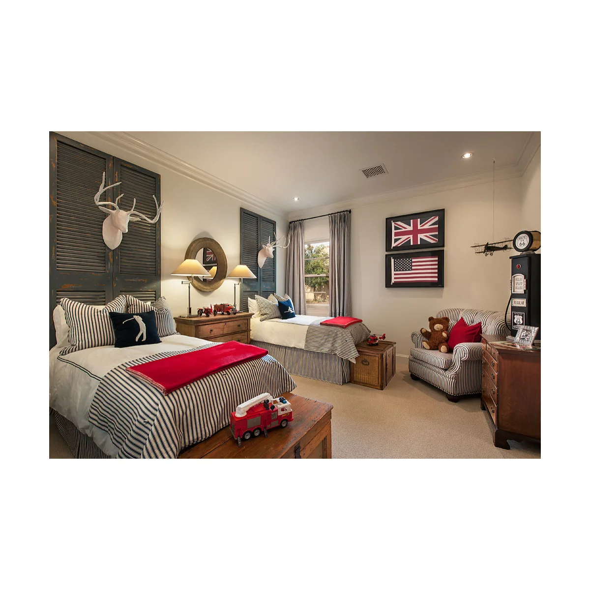 Traditional shared boy’s bedroom with twin beds, striped covers, trunks and a central bedside chest