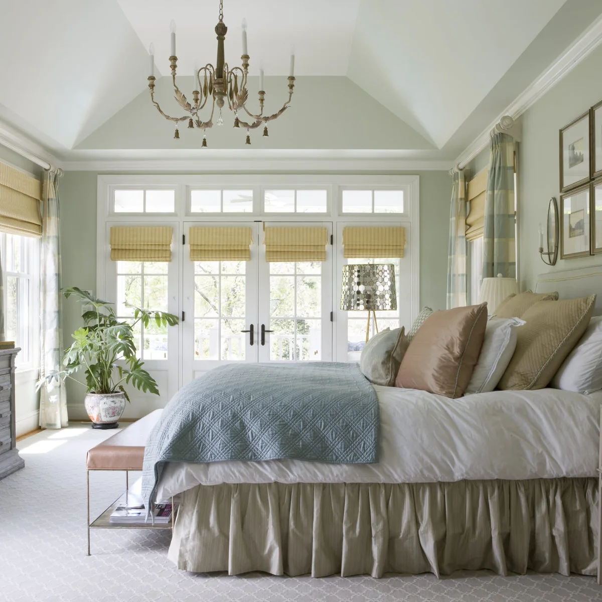 Very pale green-gray bedroom walls around white glazed doors with blue bedding and soft yellow blinds.
