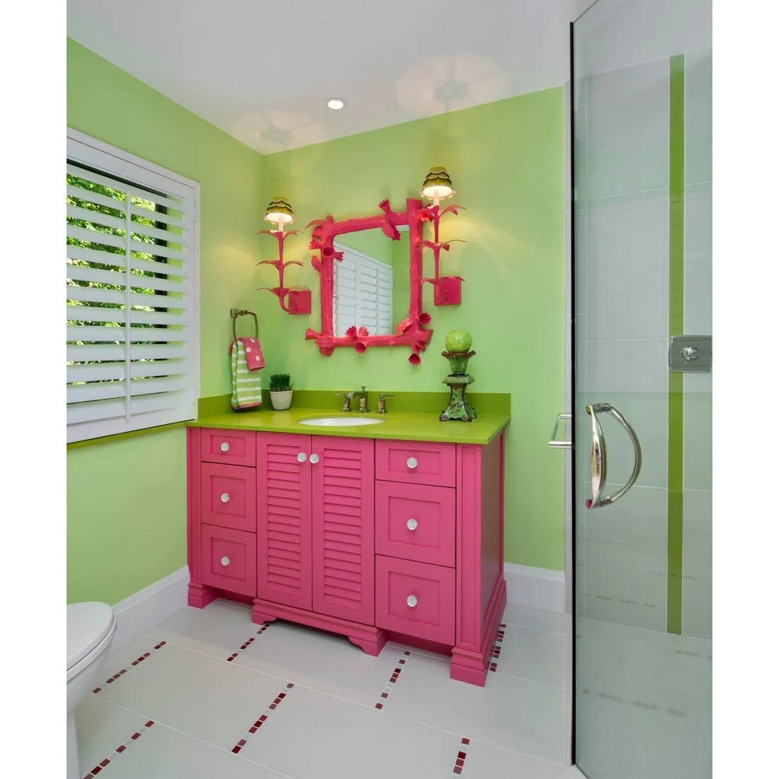 Hot pink vanity doors and a decorative pink mirror stand against lime green bathroom walls and a green counter.