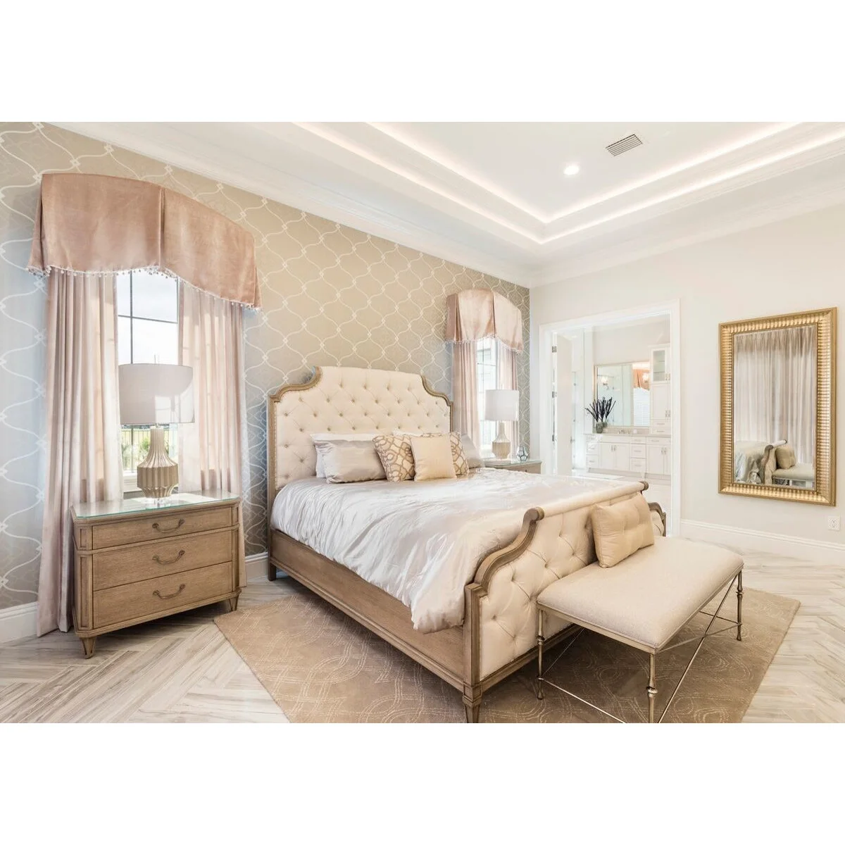 Light bedroom with a curved tufted headboard, rounded wood bedside chest and upholstered footboard