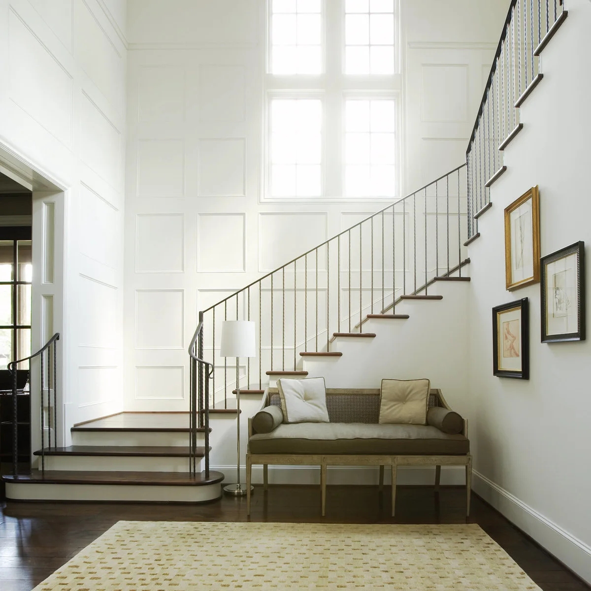Large white wall frames around tall stair-hall windows beside a curved staircase