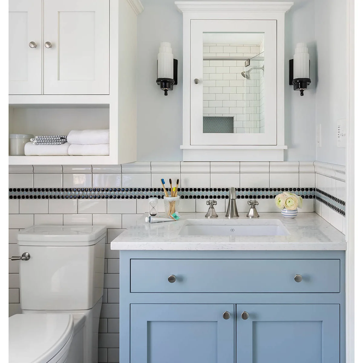 Blue vanity beneath a mirror cabinet with an open towel cubby above the toilet