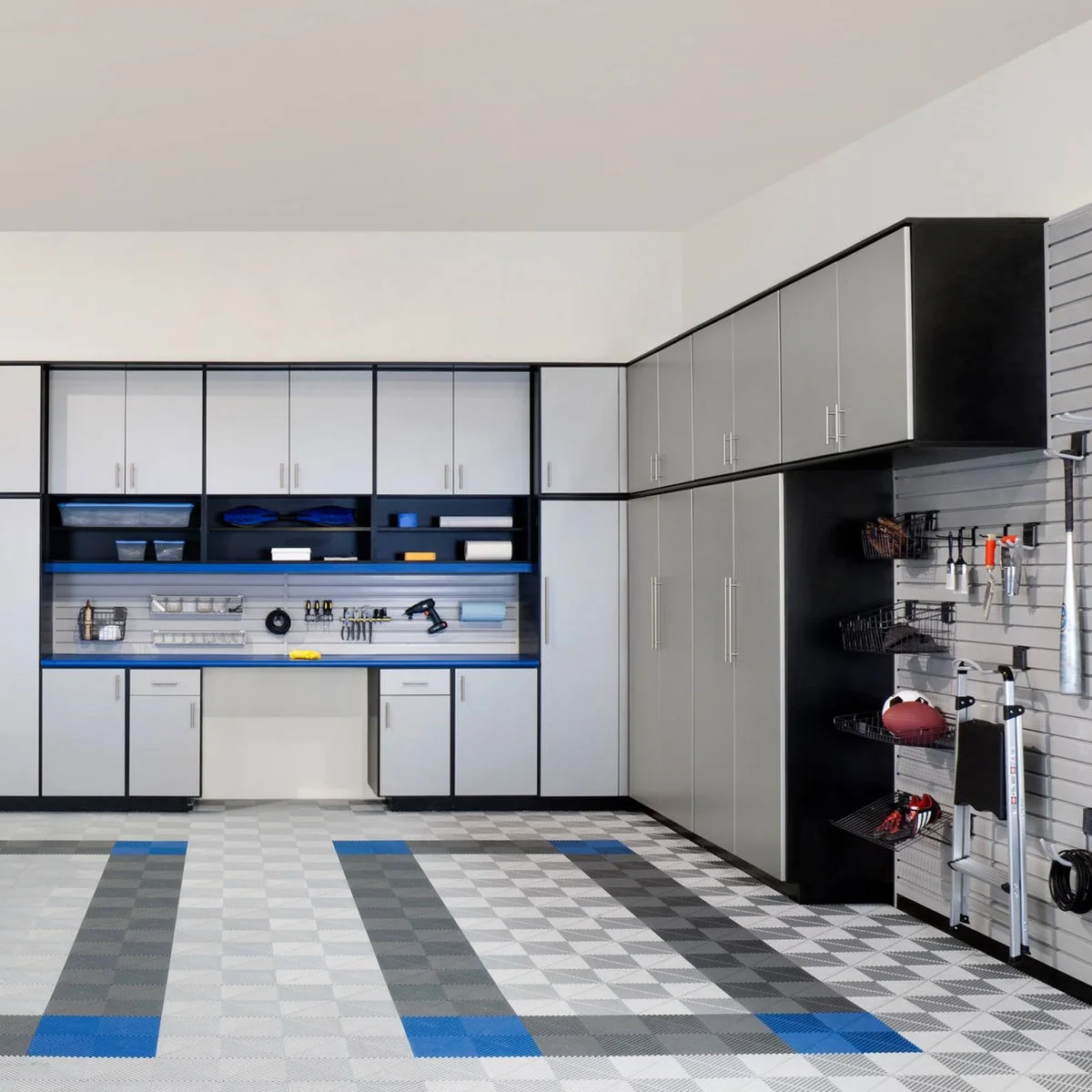 Garage wall with a blue-edged workbench, silver cabinet doors, slat-wall tools and taller storage to one side.
