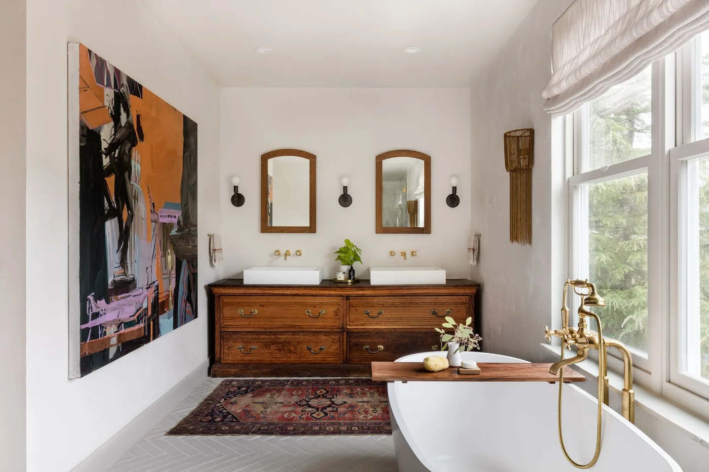 Two vessel basins on a broad wood drawer chest beside a white bath and patterned rug