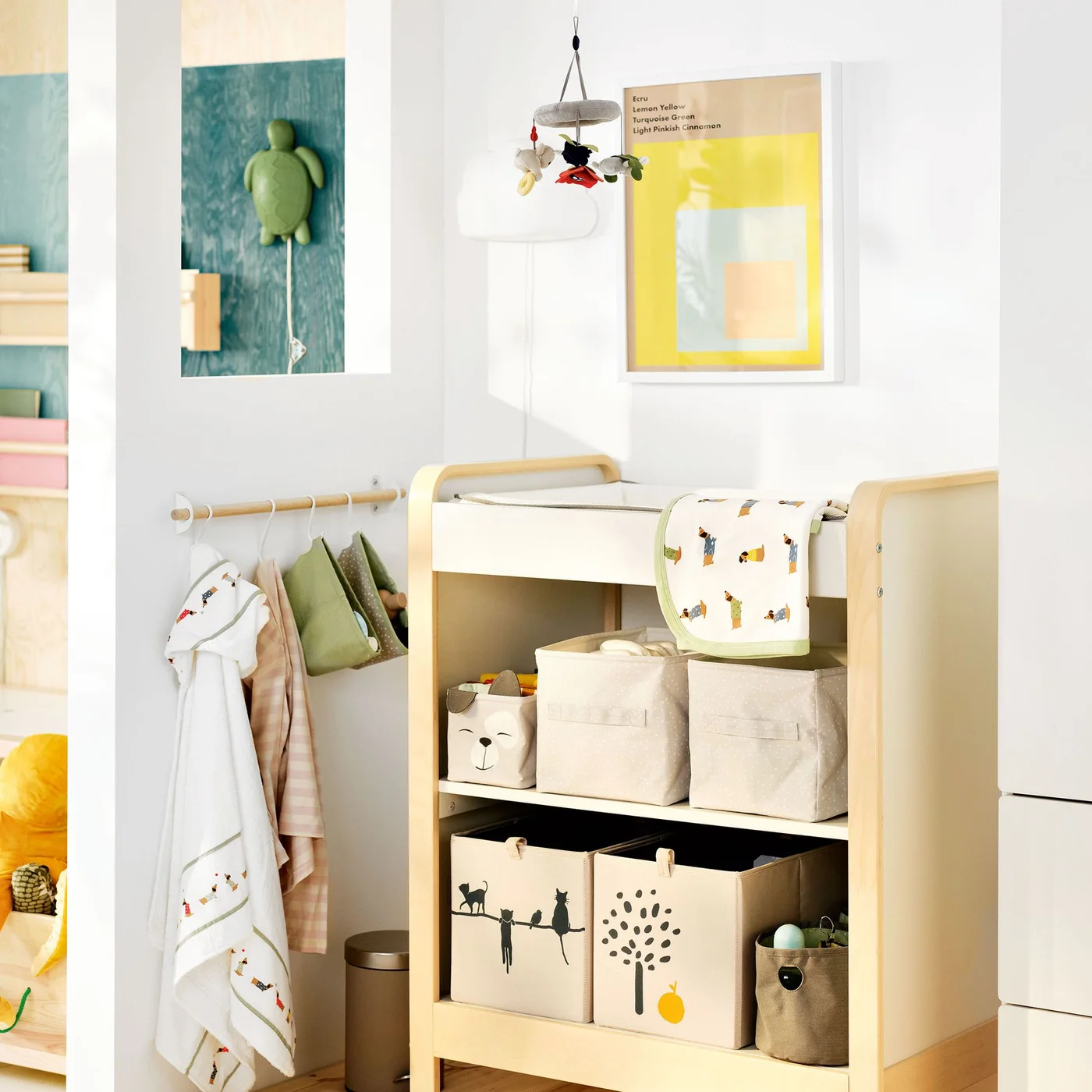 A pale changing unit holds fabric bins on two lower shelves beside a small rail of hanging clothes.