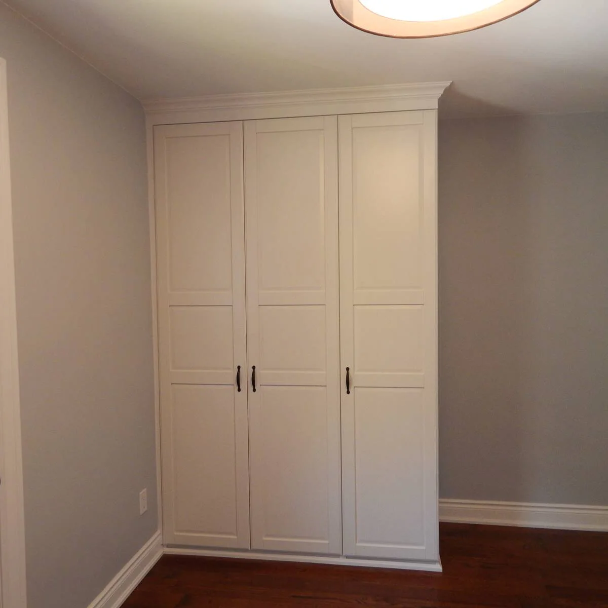 White three-door fitted PAX wardrobe with rectangular panel details and dark handles