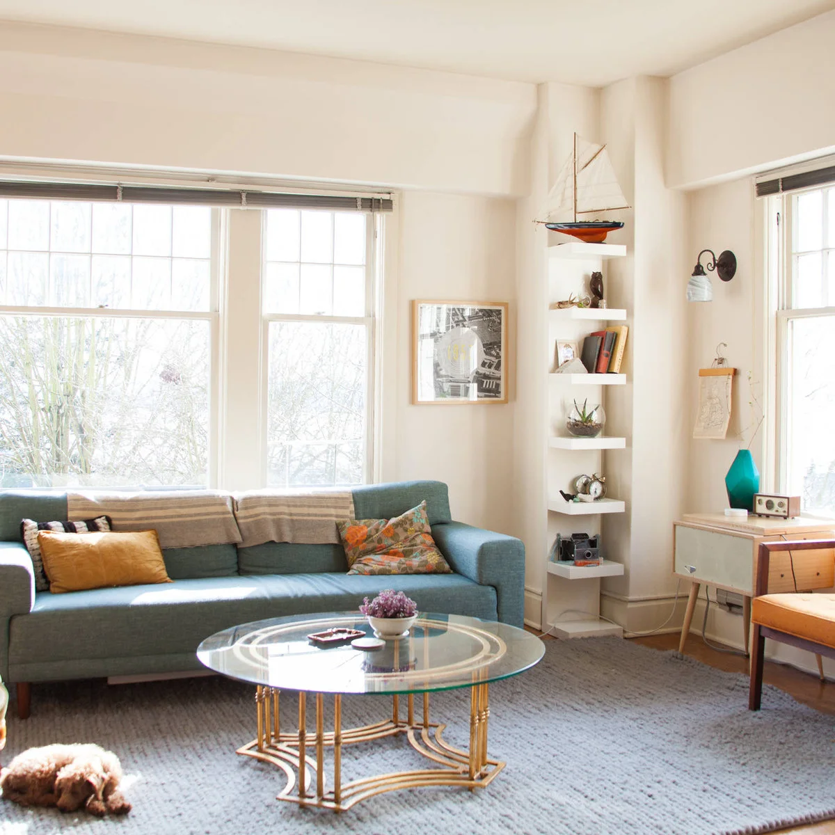 Compact white living room with a blue-green sofa and narrow corner shelves