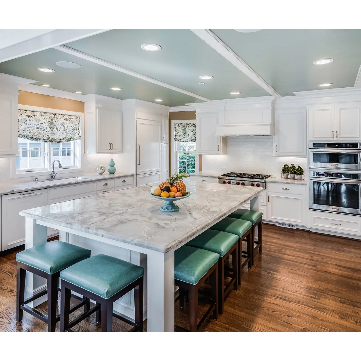 Green padded backless kitchen stools with dark wood frames around a pale island
