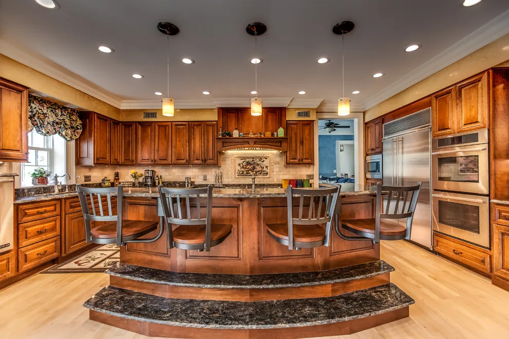 Ornate warm wood cabinets surround a large island with a raised seating area
